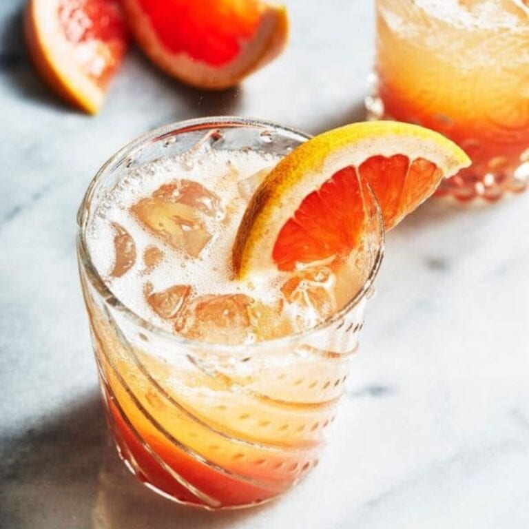 Glass of paloma cocktail garnished with a grapefruit wedge.