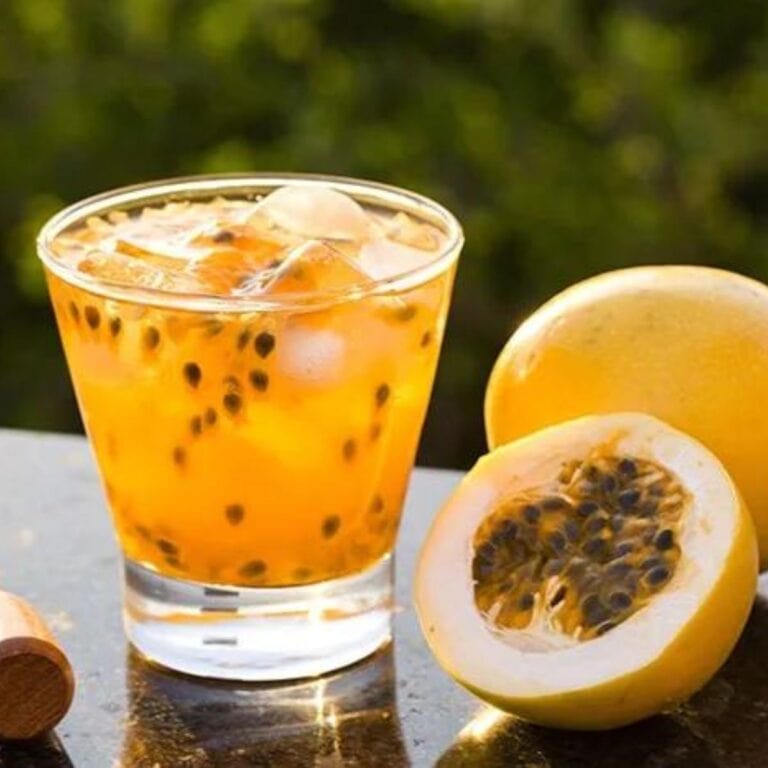 Glass of passion fruit caipiroska with passion fruit sitting next to it.