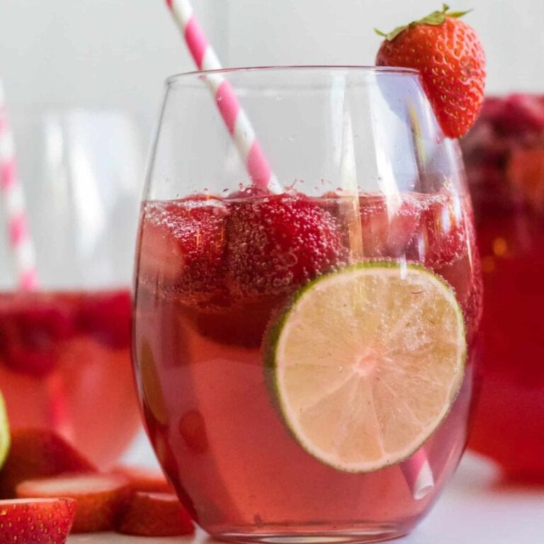 Glass of pink moscato sangria garnished with strawberries and sliced lime.