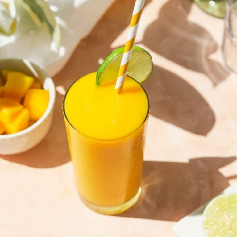 Tropical rum slushie sitting on an outdoor table with sun shining across it.