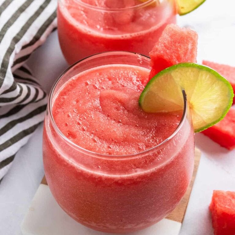 Watermelon frose in a glass garnished with slice of lime and watermelon.