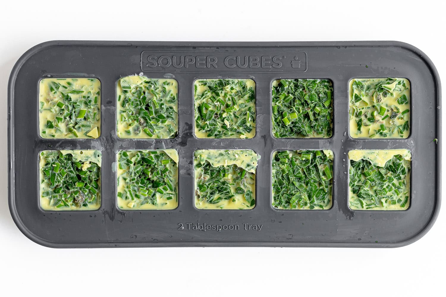 Frozen herb cubes in silicone ice cube tray.