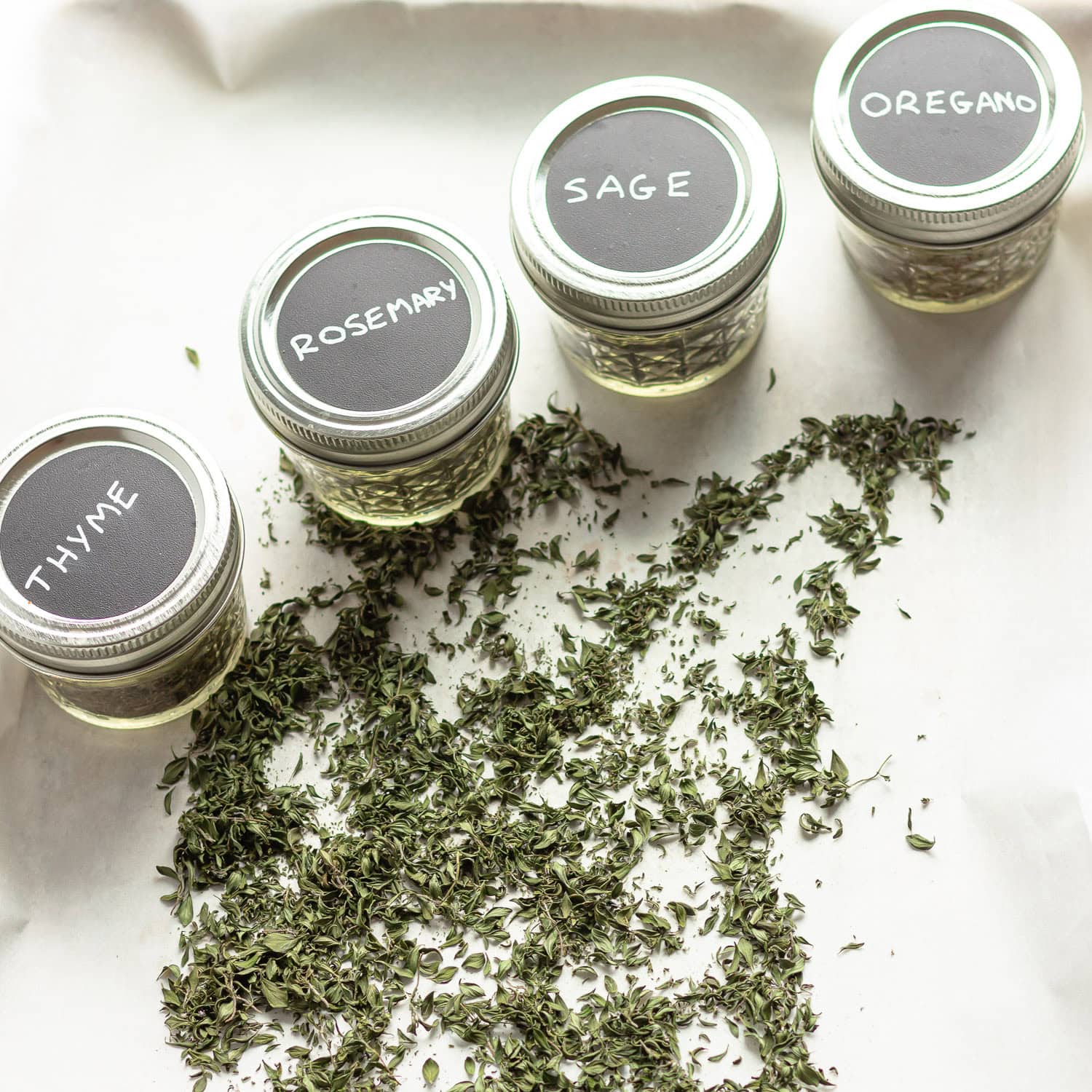 Dried herbs in small mason jars with labelled lids.