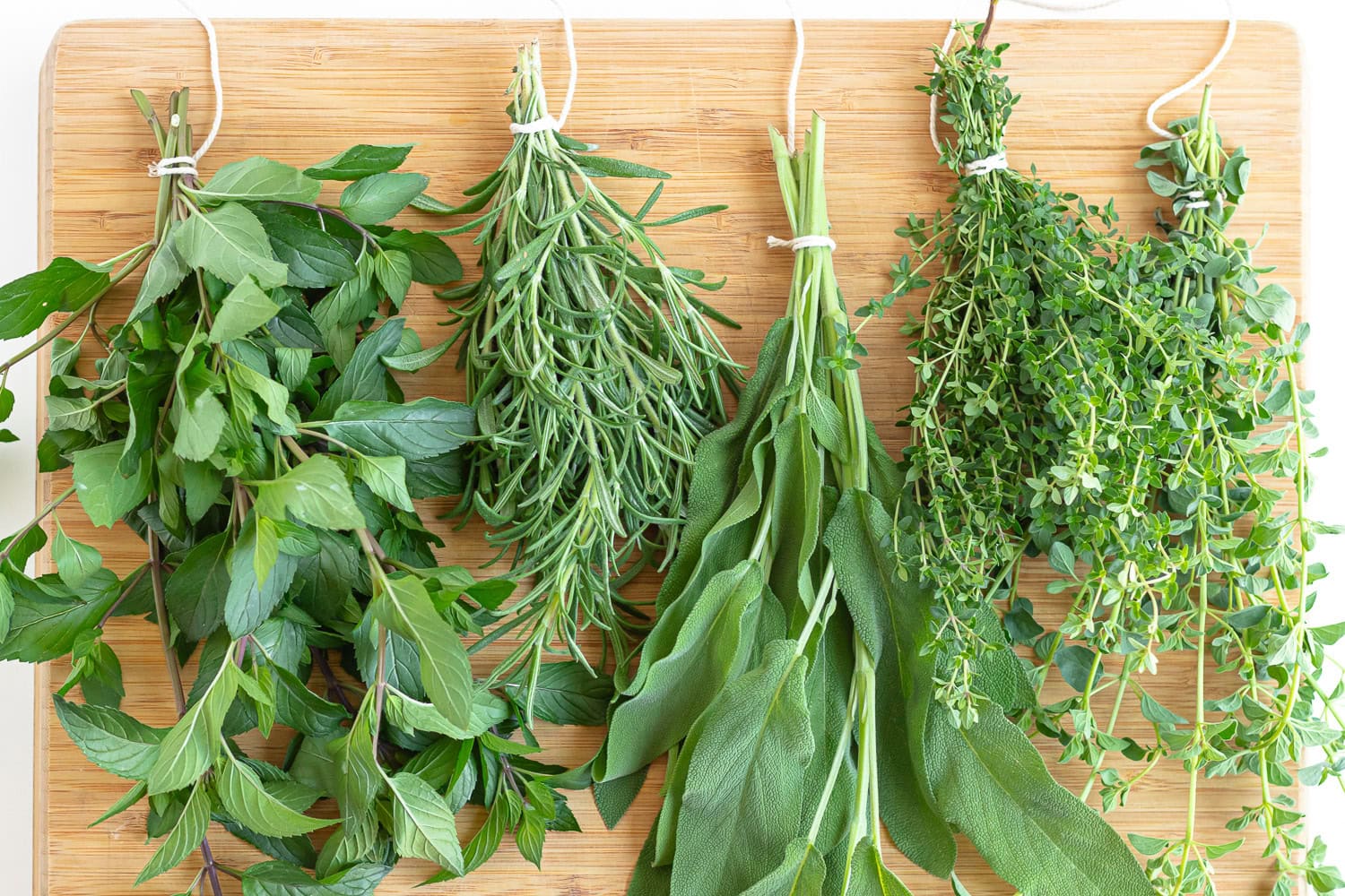 Tied herb bundles sitting on a wooden cutting board.