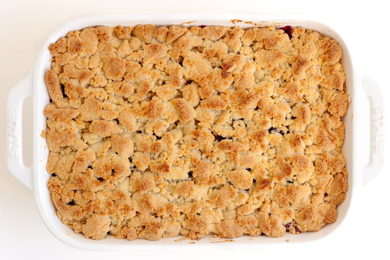 Baked apple blackberry crumble in a white baking dish.