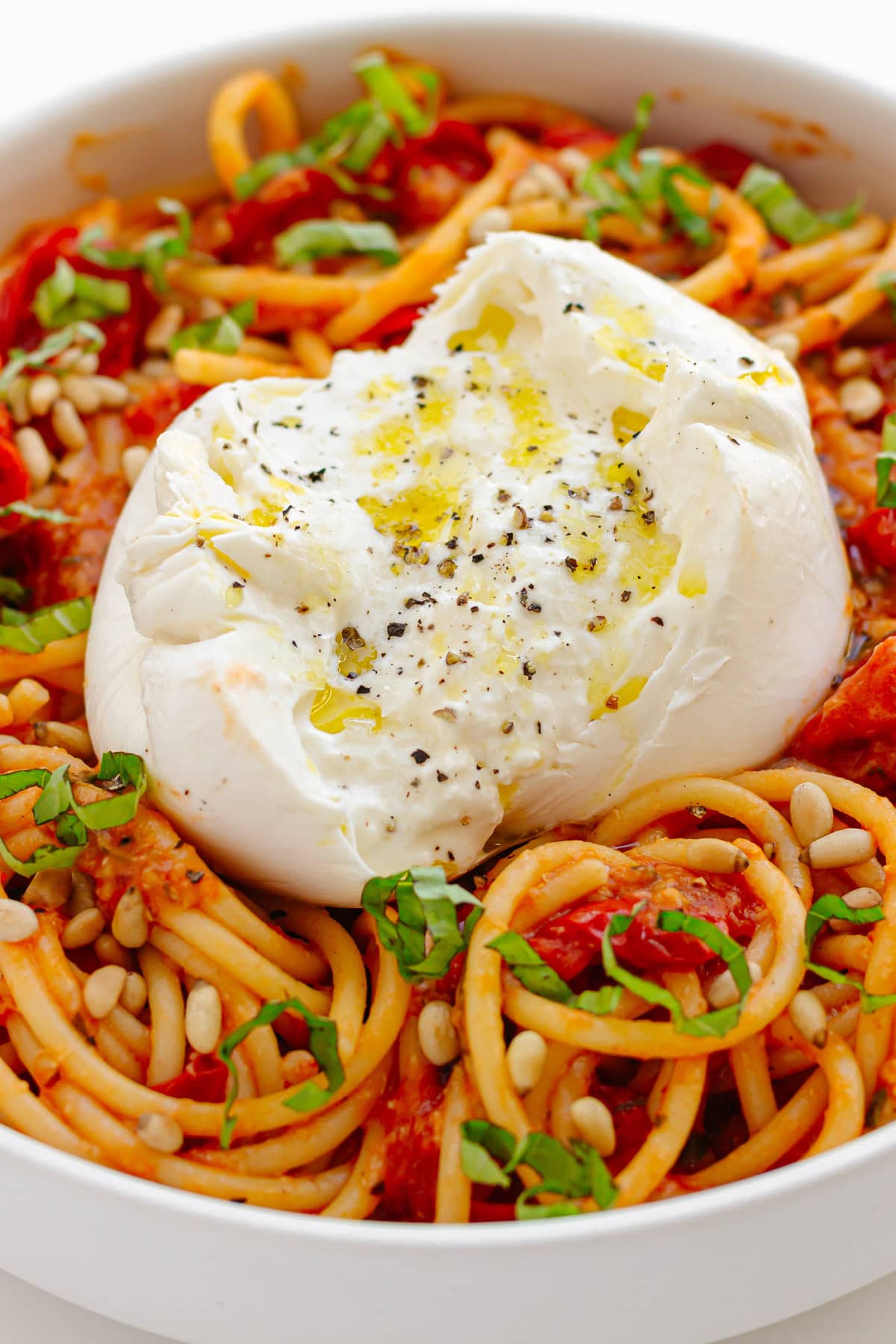 Serving bowl of cherry tomato pasta with burrata on top.