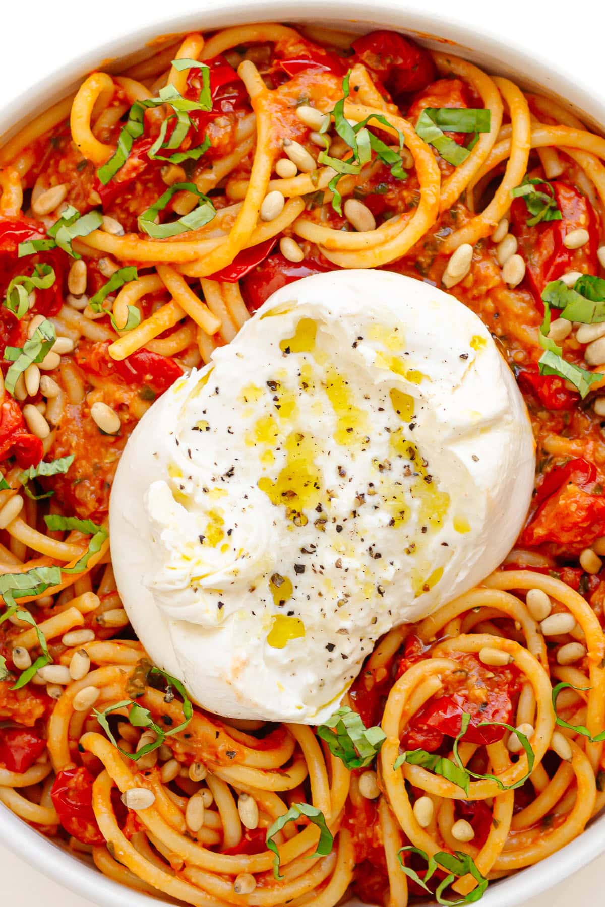 Large white serving bowl of burrata pasta with cherry tomato sauce.