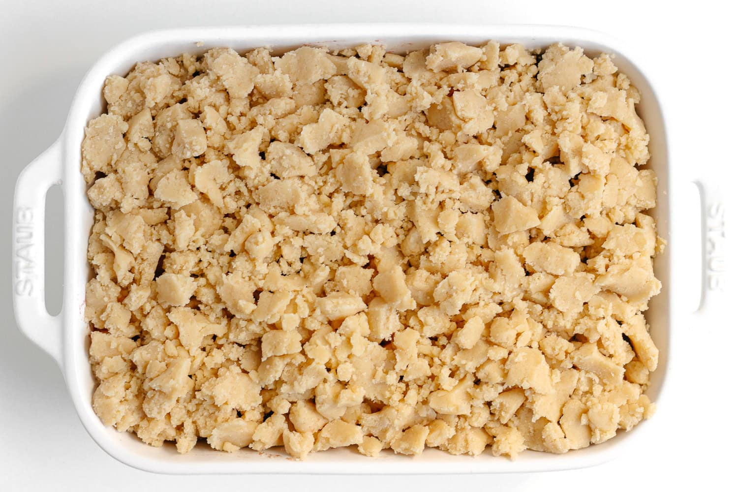 Unbaked apple blackberry crumble in a white baking dish.