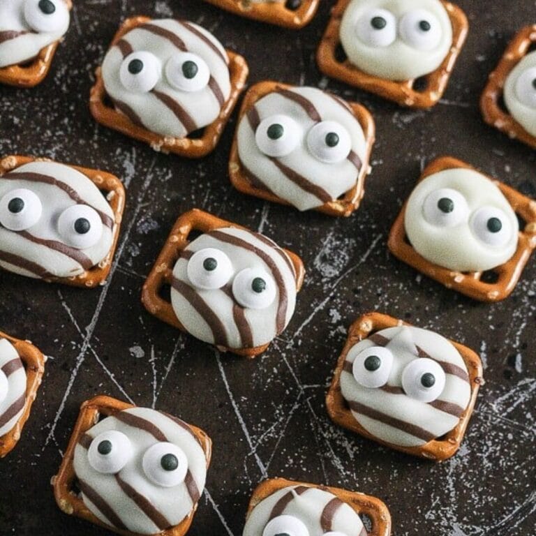 Googly eye pretzel kisses on a black surface.