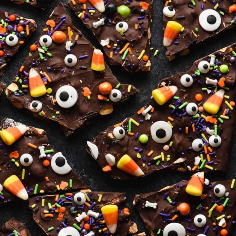 Halloween chocolate bark broken into pieces on a black surface.