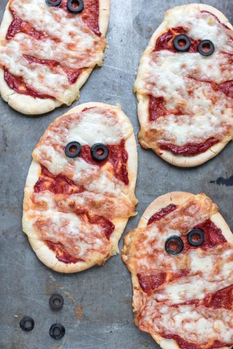 Naan bread mummy pizzas on a gray surface.