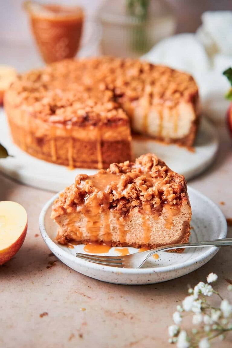 Apple crisp cheesecake with a slice cut out and placed on a small dessert plate.