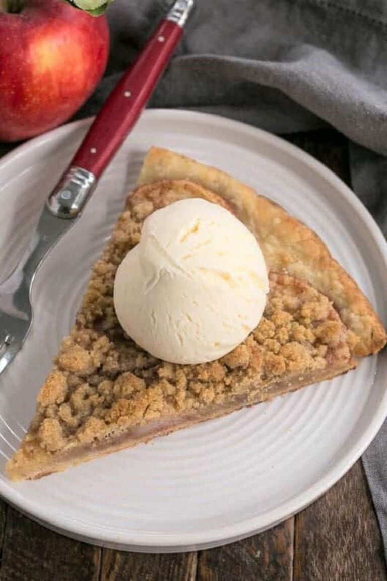 Slice of apple pie pizza with scoop of vanilla ice cream on top.