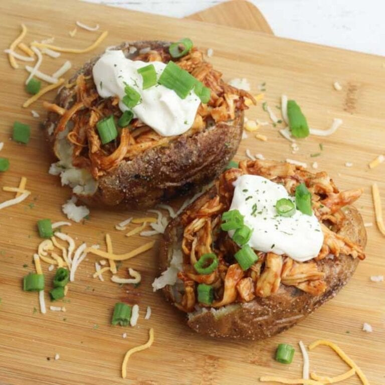 Two BBQ turkey stuffed baked potatoes on a wooden board.