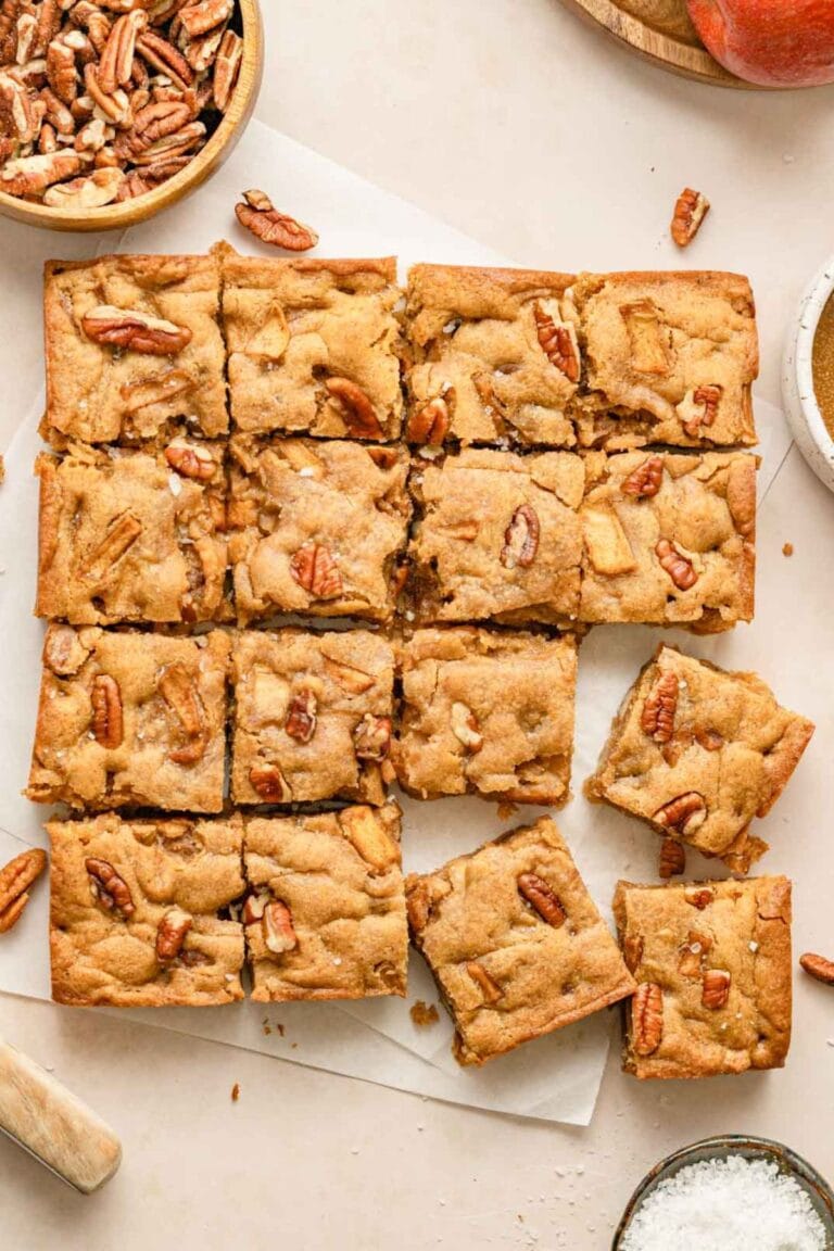 Brown butter apple blondies cut into squares sitting on parchment paper.