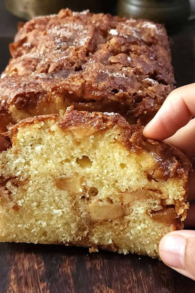 Hand holding a slice of cinnamon apple bread.