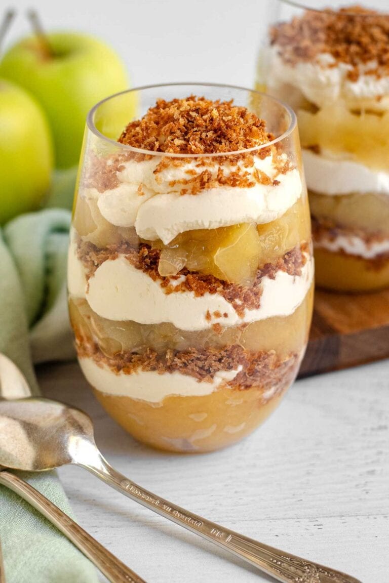 Apple crumble parfait in a glasses with 2 spoons in front.