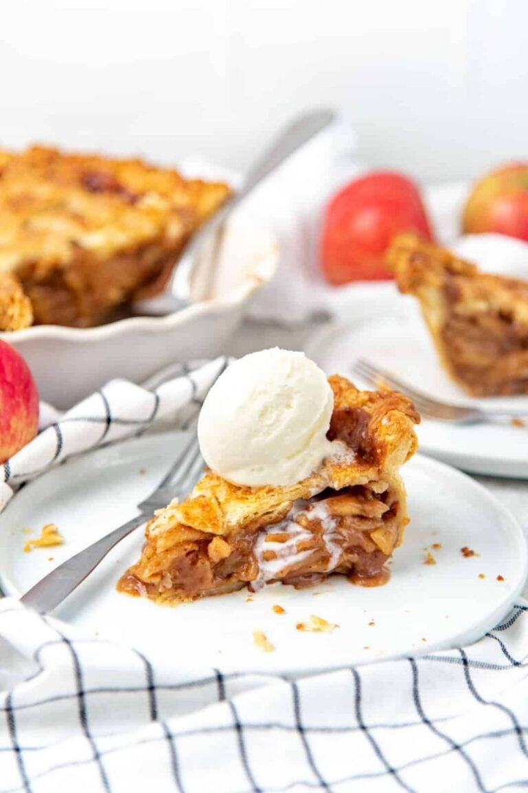 Slice of butterscotch apple pie topped with a scoop of vanilla ice cream.
