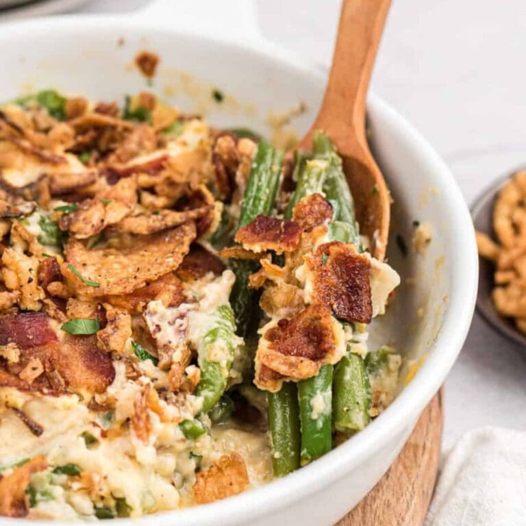 Creamy green bean casserole with bacon in a white serving dish.