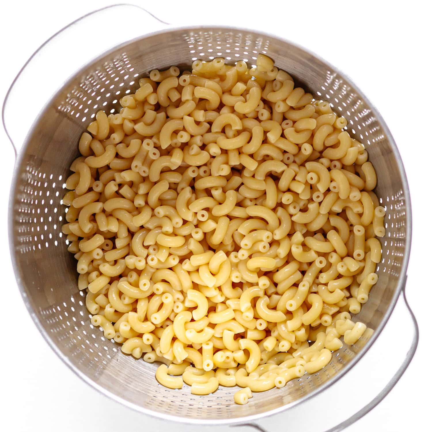 Cooked macaroni draining in a stainless steel colander.