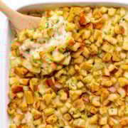 Scoop of gouda mac and cheese being lifted from white casserole dish.