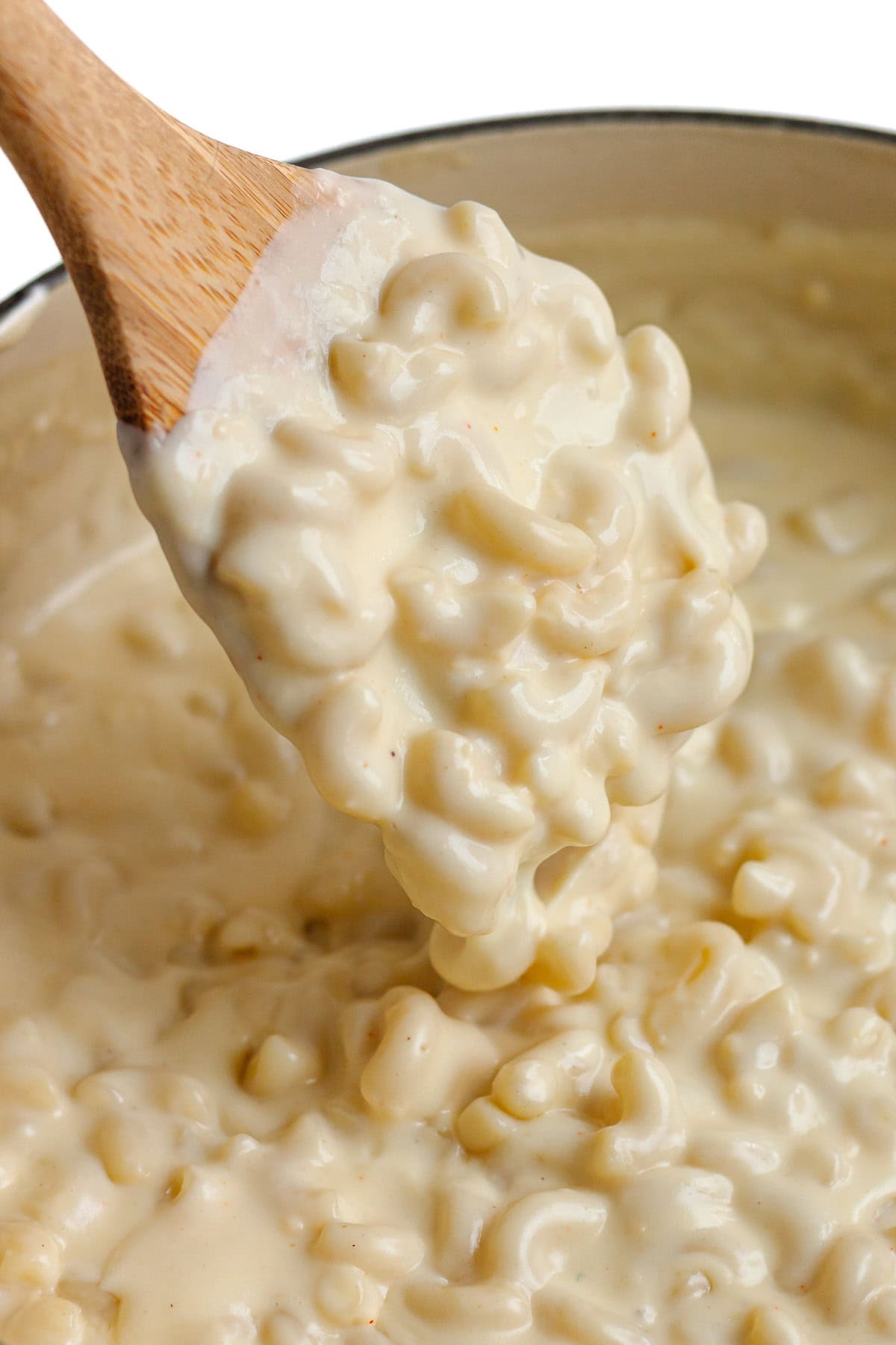 Stovetop gouda mac and cheese being stirred with wooden spoon.