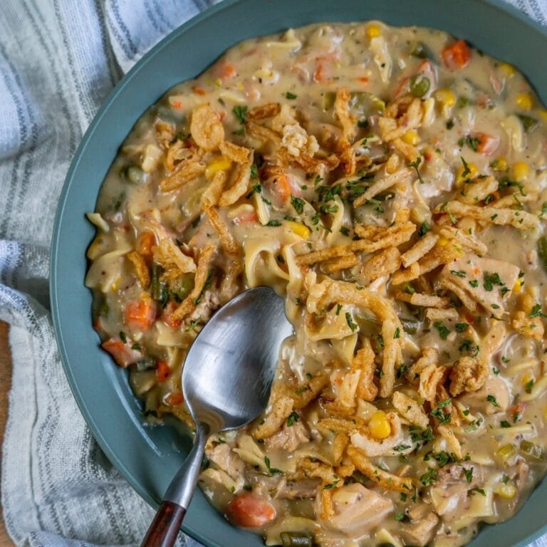 Leftover turkey stroganoff on a blue plate with spoon.