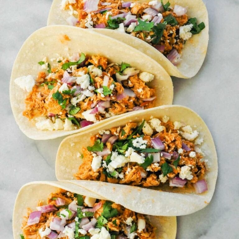Four turkey tacos on a marble slab.