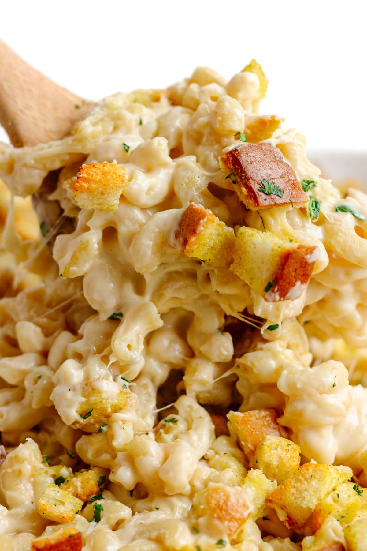 Macaroni and cheese with gouda and crispy bread topping being scooped up.