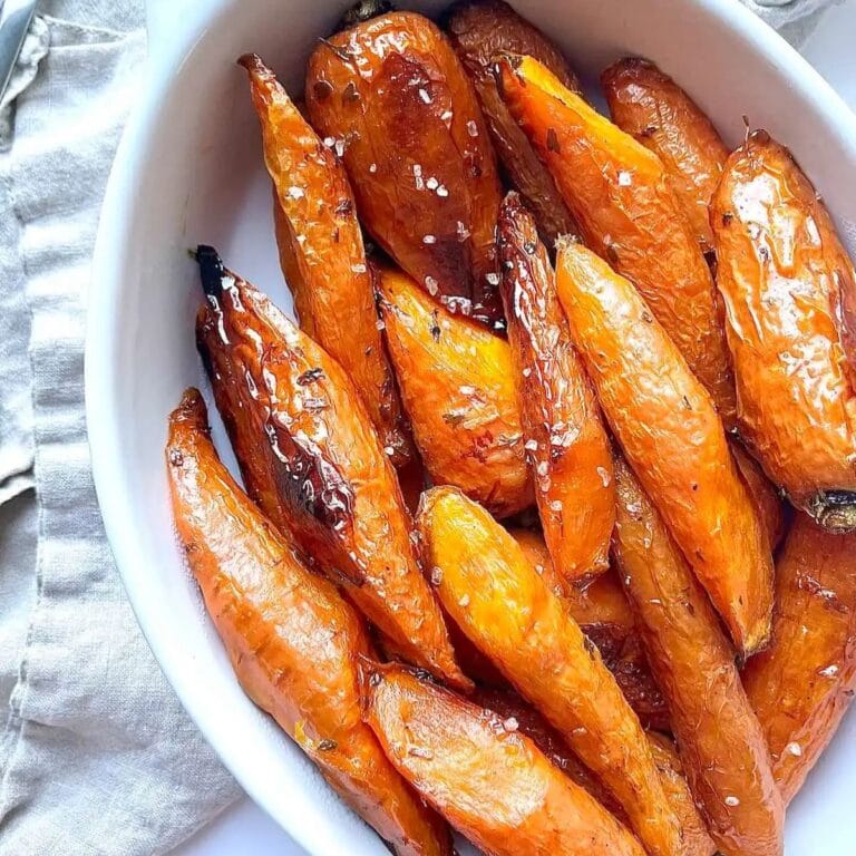 Maple glazed roasted carrots in a white serving dish.