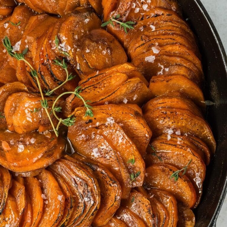 Closeup of orange glazed sweet potato slices in a cast iron skillet.