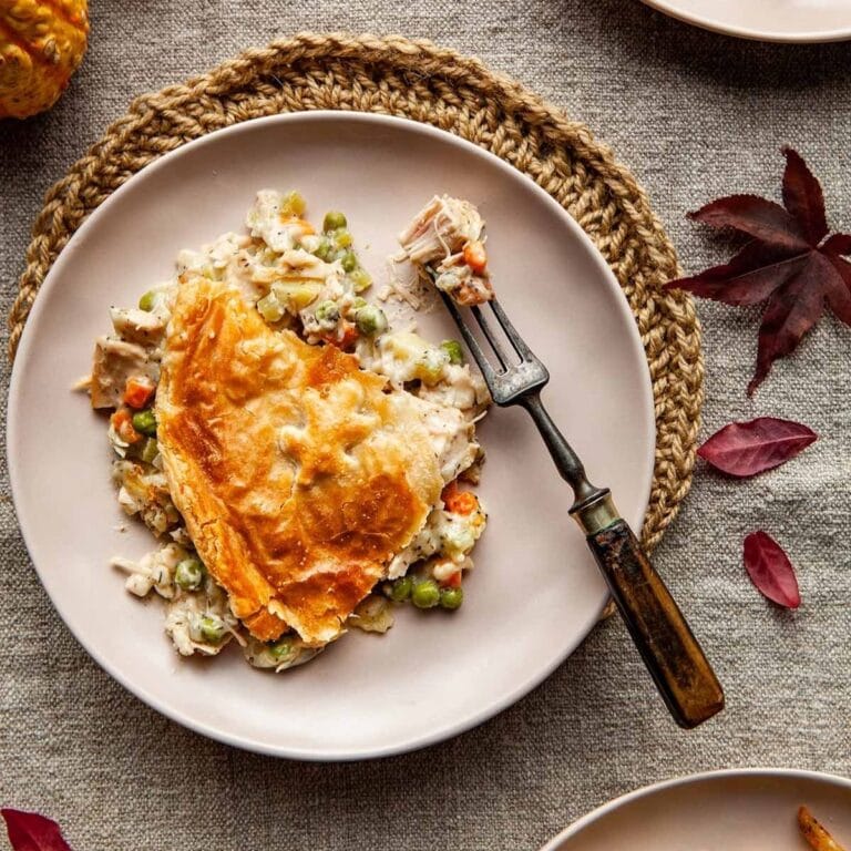 Slice of puff pastry turkey pot pie on a plate with a fork.