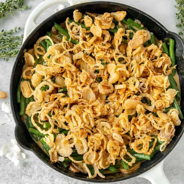 Green bean casserole in a cast iron skillet topped with crispy shallots.