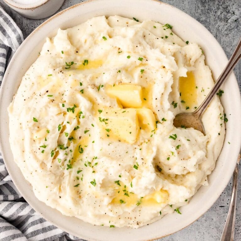 Sour cream mashed potatoes in a serving bowl with serving spoon.