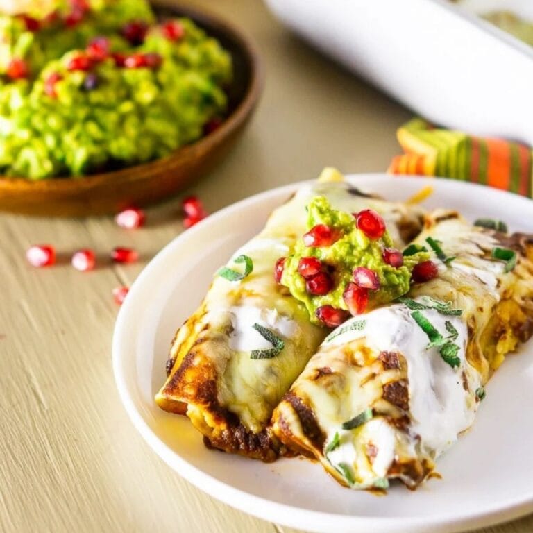 Thanksgiving enchiladas on a white plate garnished with pomegranate arils.