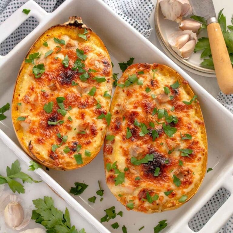 Two turkey alfredo spaghetti squash boats in a white casserole dish.