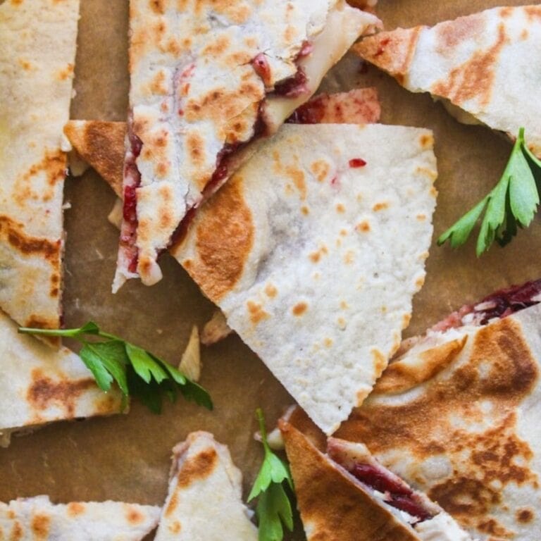 Turkey cranberry brie quesadilla cut into triangles on a board.