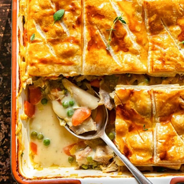Casserole dish of turkey marsala pot pie with one slice missing.