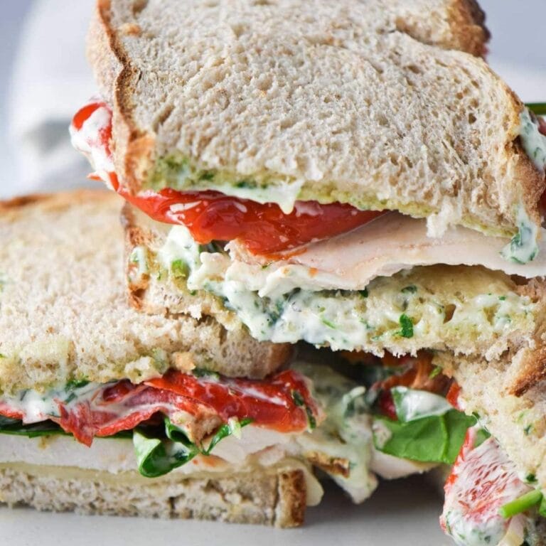 Two turkey pesto sandwiches stacked.