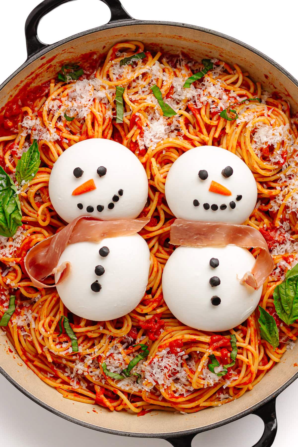 Spaghetti and tomato sauce in a cast iron braiser with two burrata snowmen on top.
