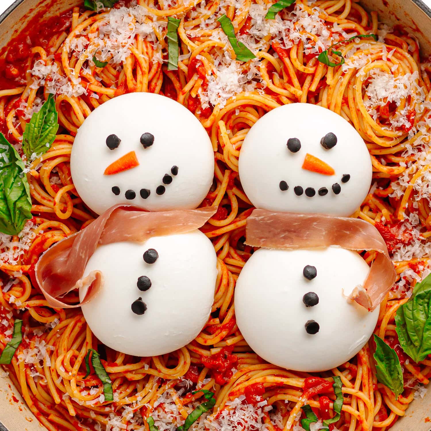 Spaghetti topped with two burrata snowmen.