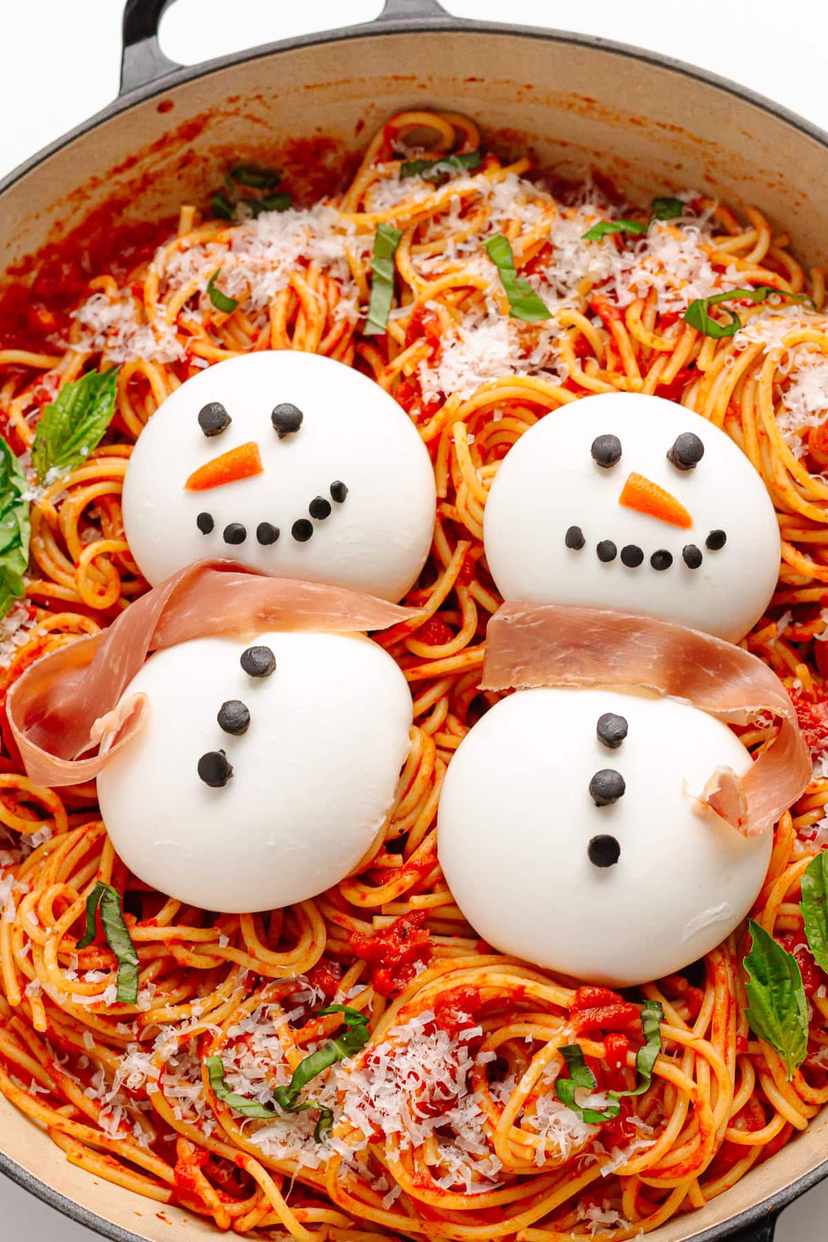 Spaghetti topped with two snowmen made from burrata cheese.