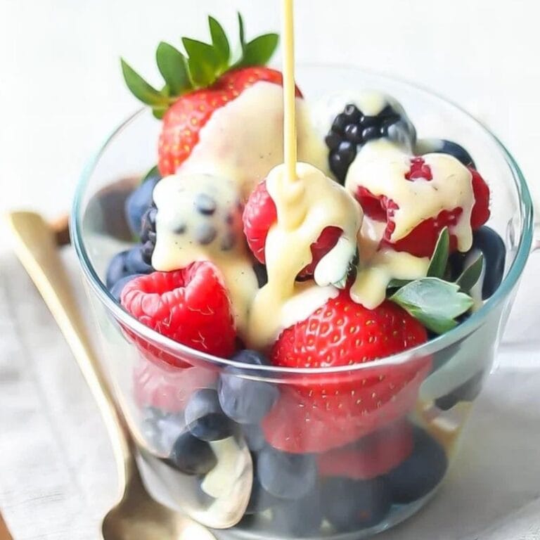 Creme Anglaise being poured over a bowl of fresh berries.