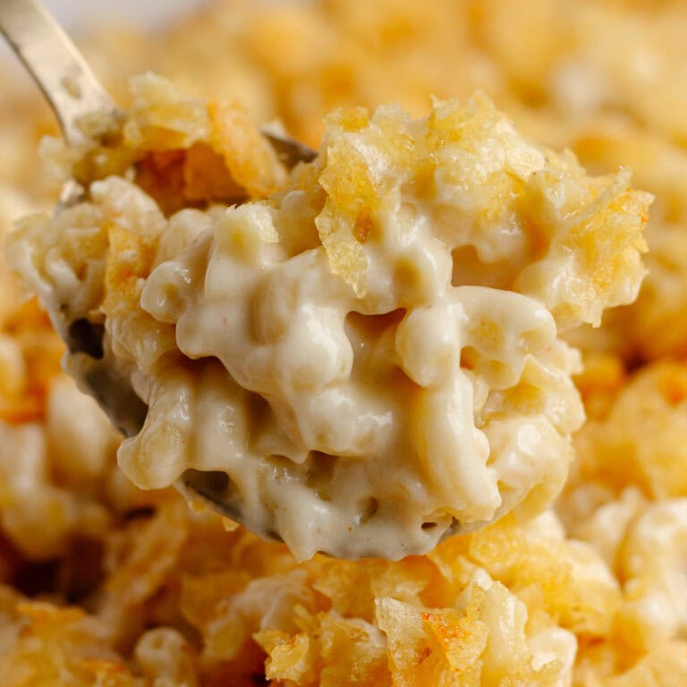 Spoon of white cheddar cheese macaroni and cheese with chip topping.