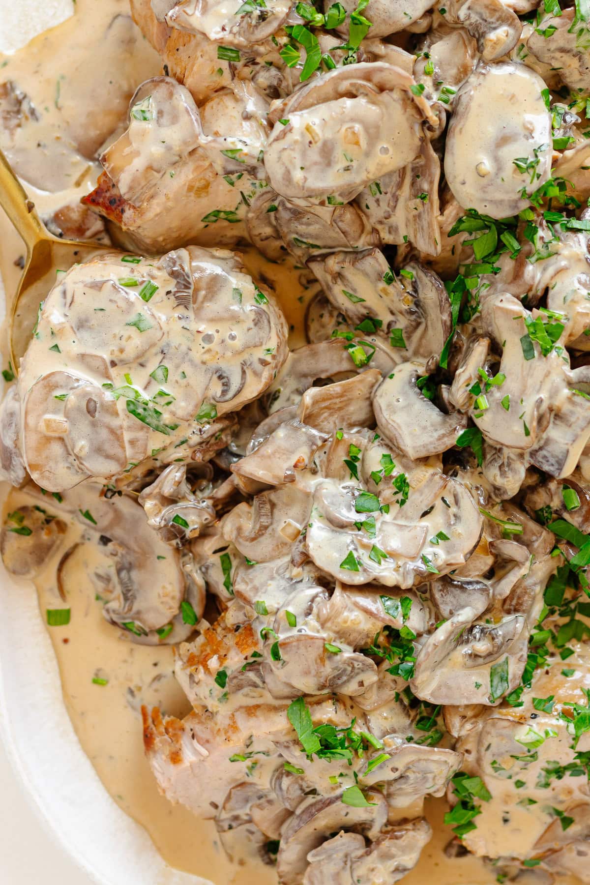 Creamy mushroom pork tenderloin garnished with chopped parsley and chives.
