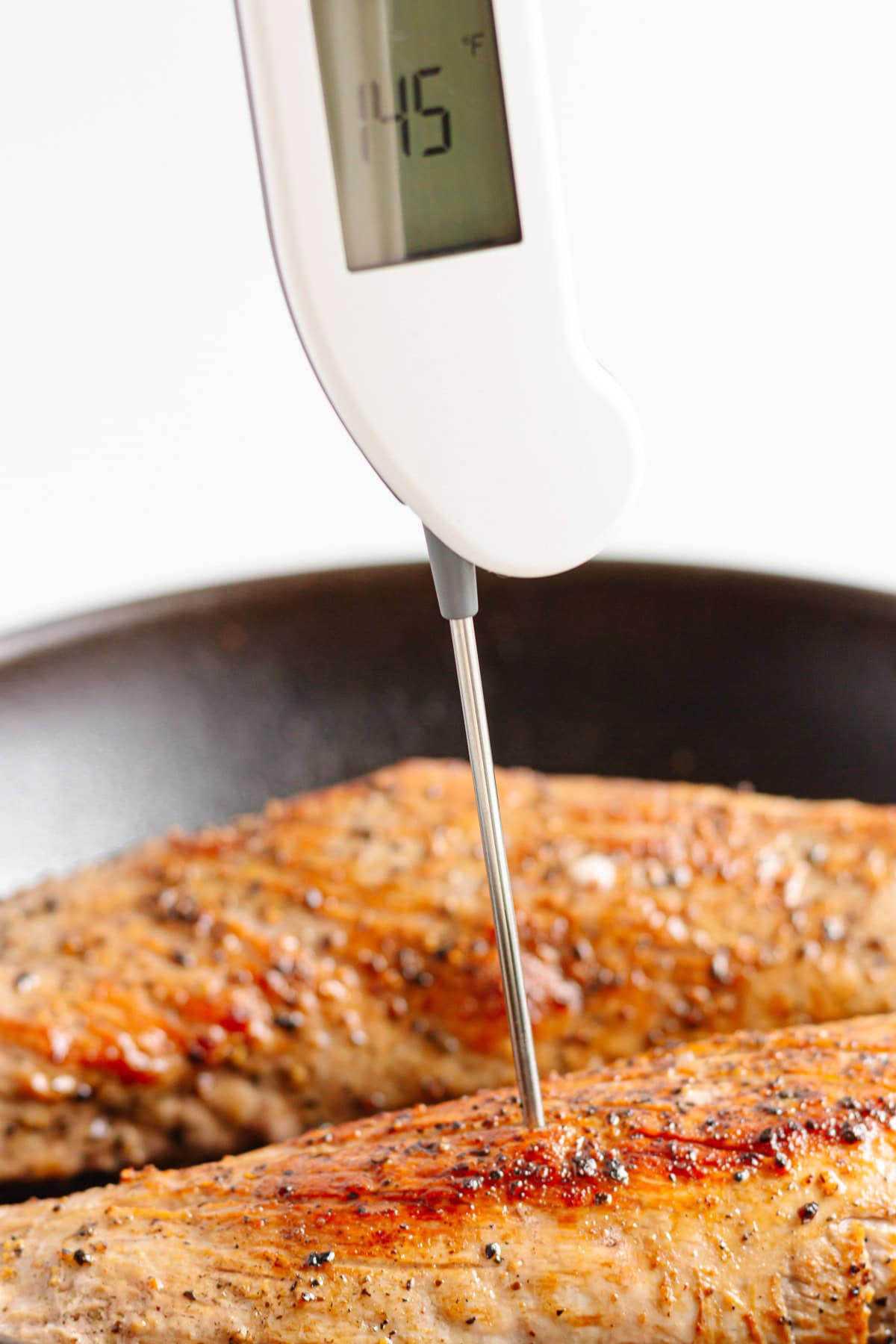 Digital meat thermometer checking pork tenderloin temperature.