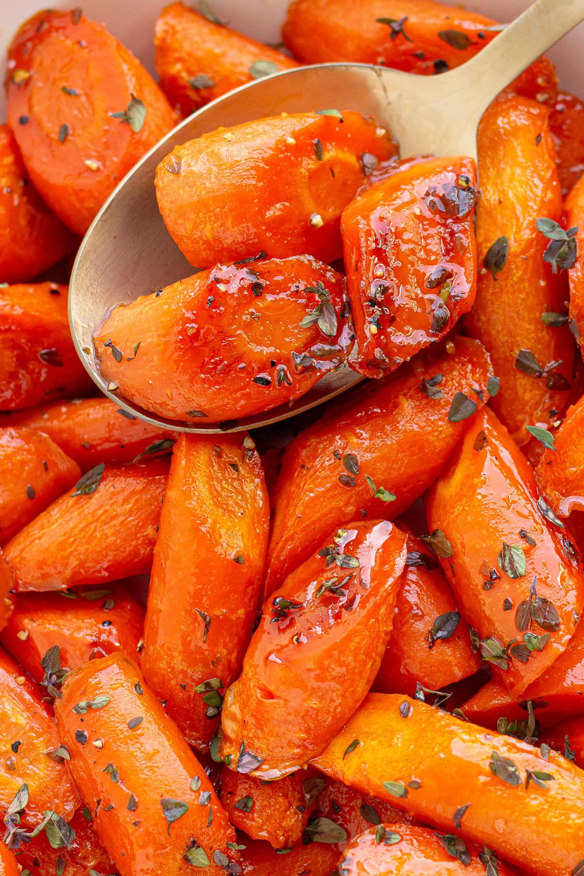 Serving spoon scooping up some honey roasted carrots.