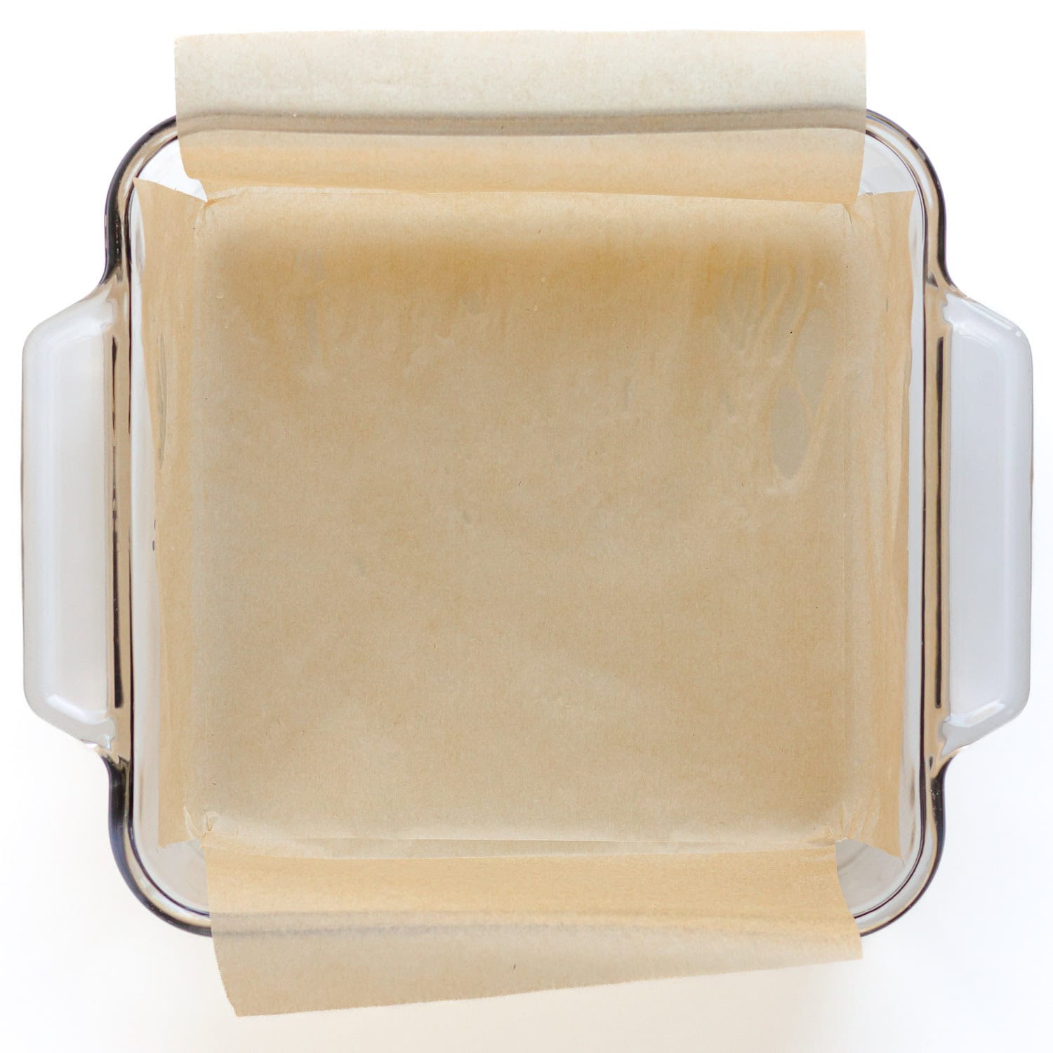 Square glass baking dish lined with parchment paper.