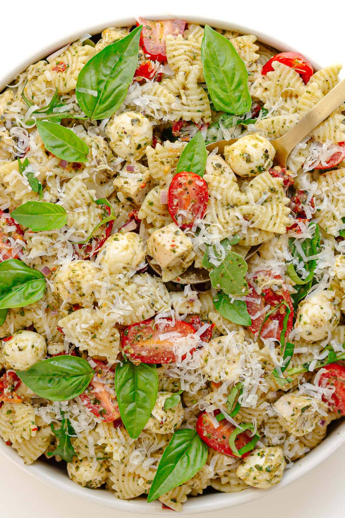Chicken pesto pasta salad in a white serving bowl.