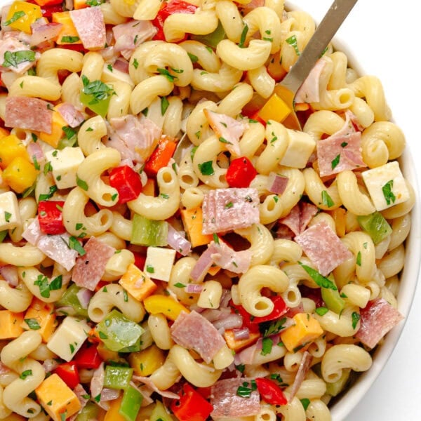 My go-to pasta salad in a white serving bowl with serving spoon.